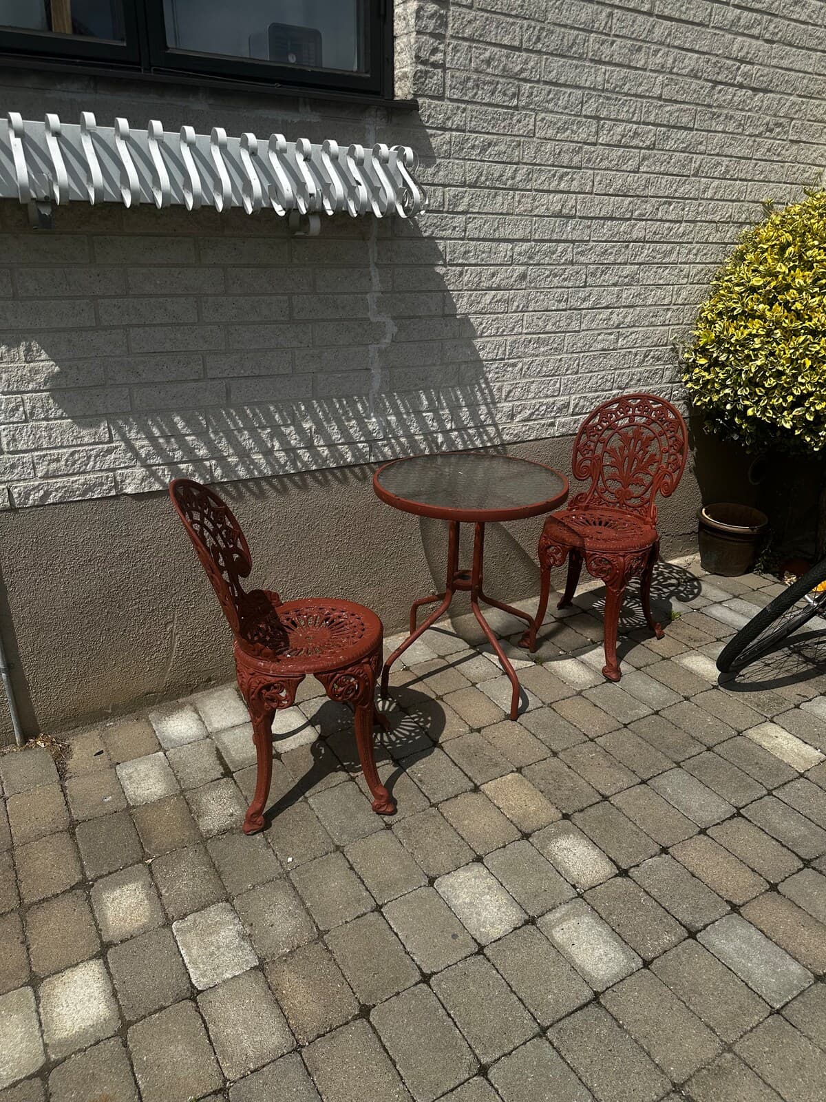 Charmig uteplats med elegant röd möblering och skugga från moderna solskydd. Perfekt för avkoppling och njutning av gårdsytans lugna miljö.