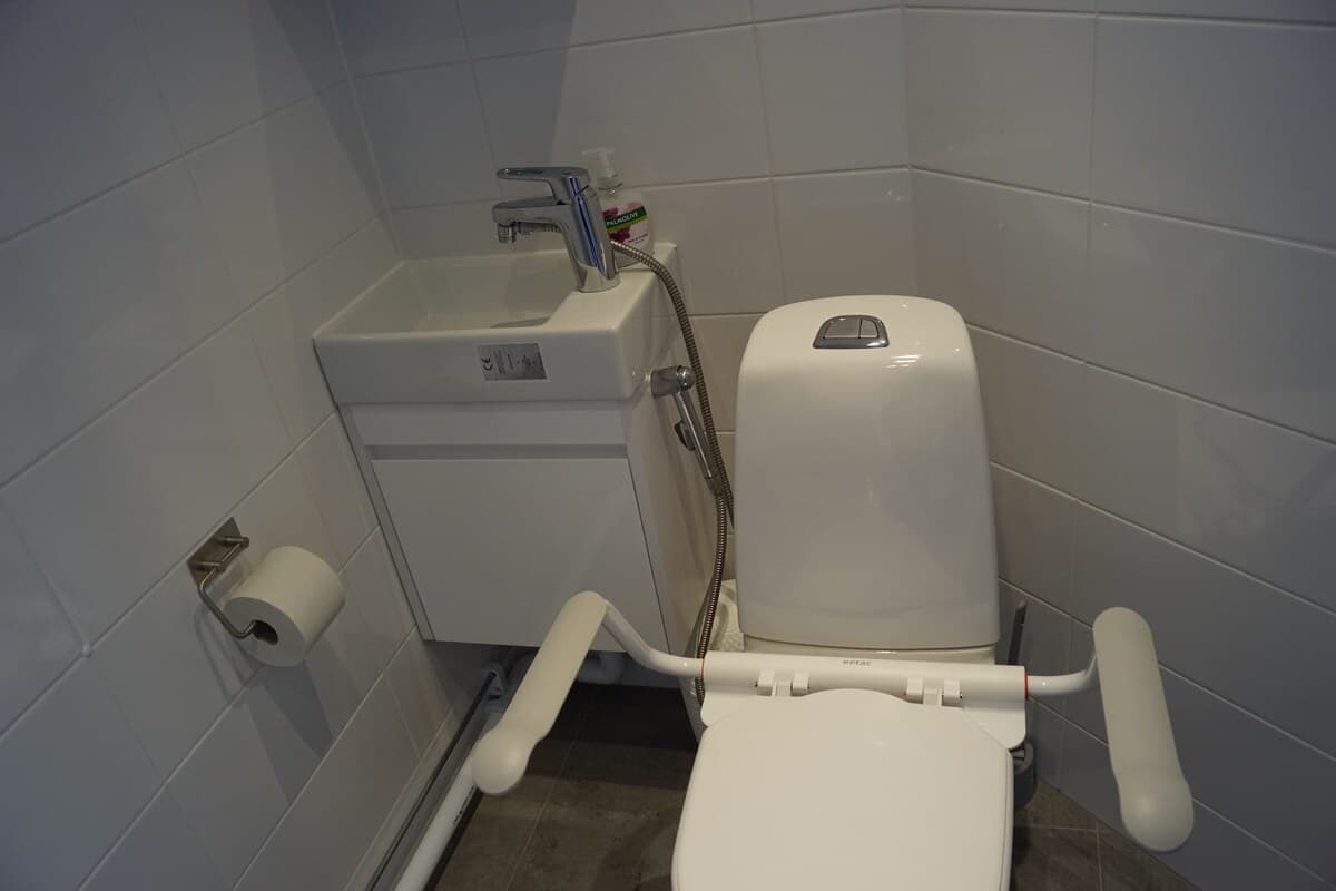 Modernt och rent badrum med japanskt toalettsystem, liten handtvätt och spegel. Perfekt för bekväm vistelse.